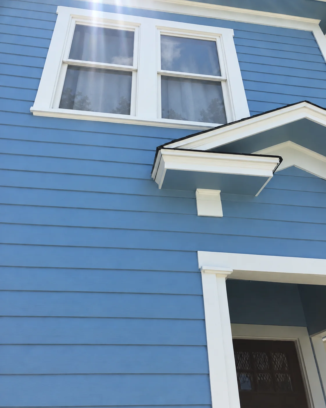 Blue exterior after siding repair, painting, and window trim restoration
