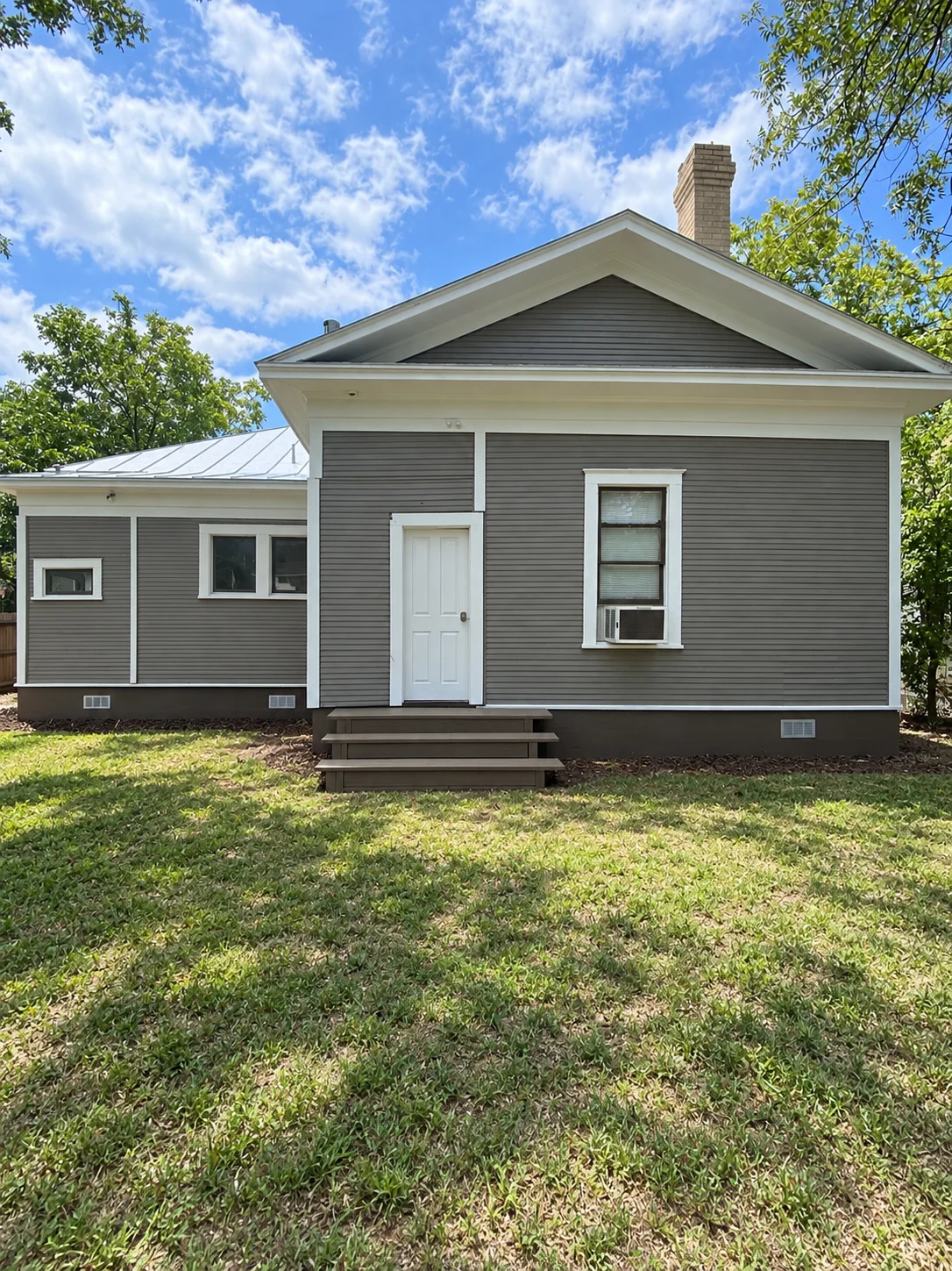 Restored gray home exterior after siding repair and painting
